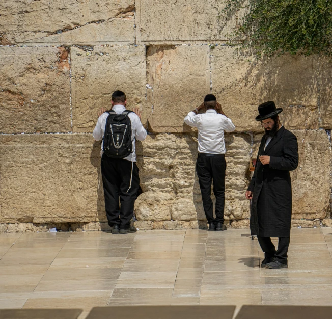 four men wearing hats are at the western wall