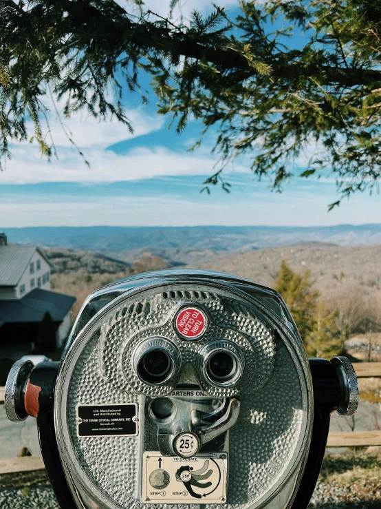 a parking meter overlooking a mountain valley with a telescope attached to it