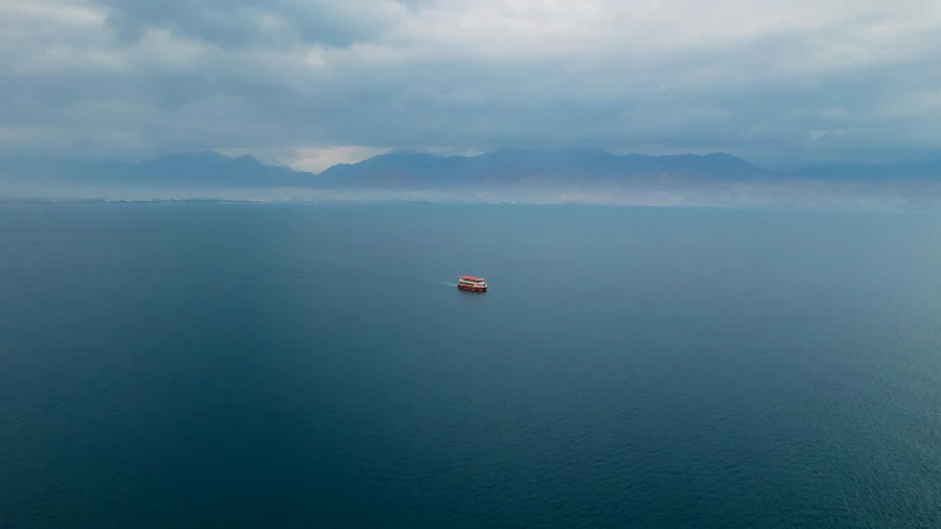 a boat is floating in a lake beneath some dark clouds