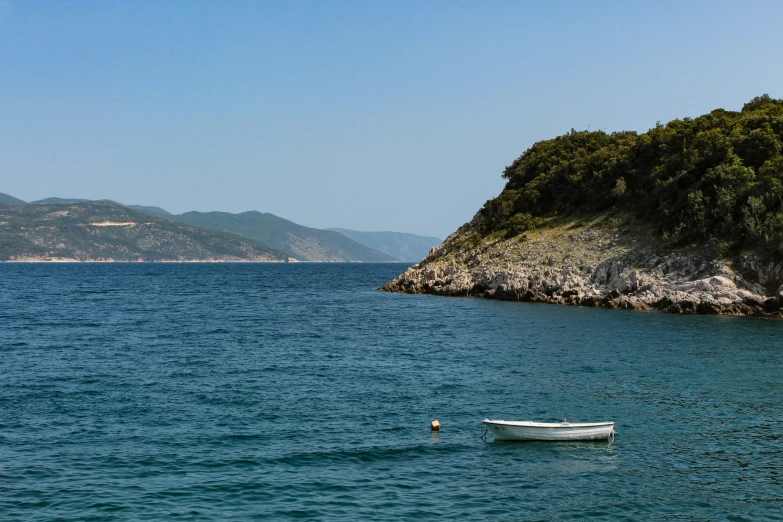 two white boats floating on top of the ocean next to an island