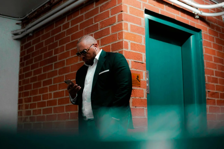 a bald man in a suit and tie is looking at his cell phone