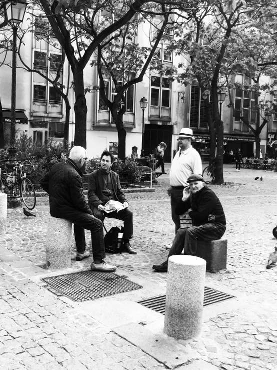 a group of people sitting on benches near some buildings
