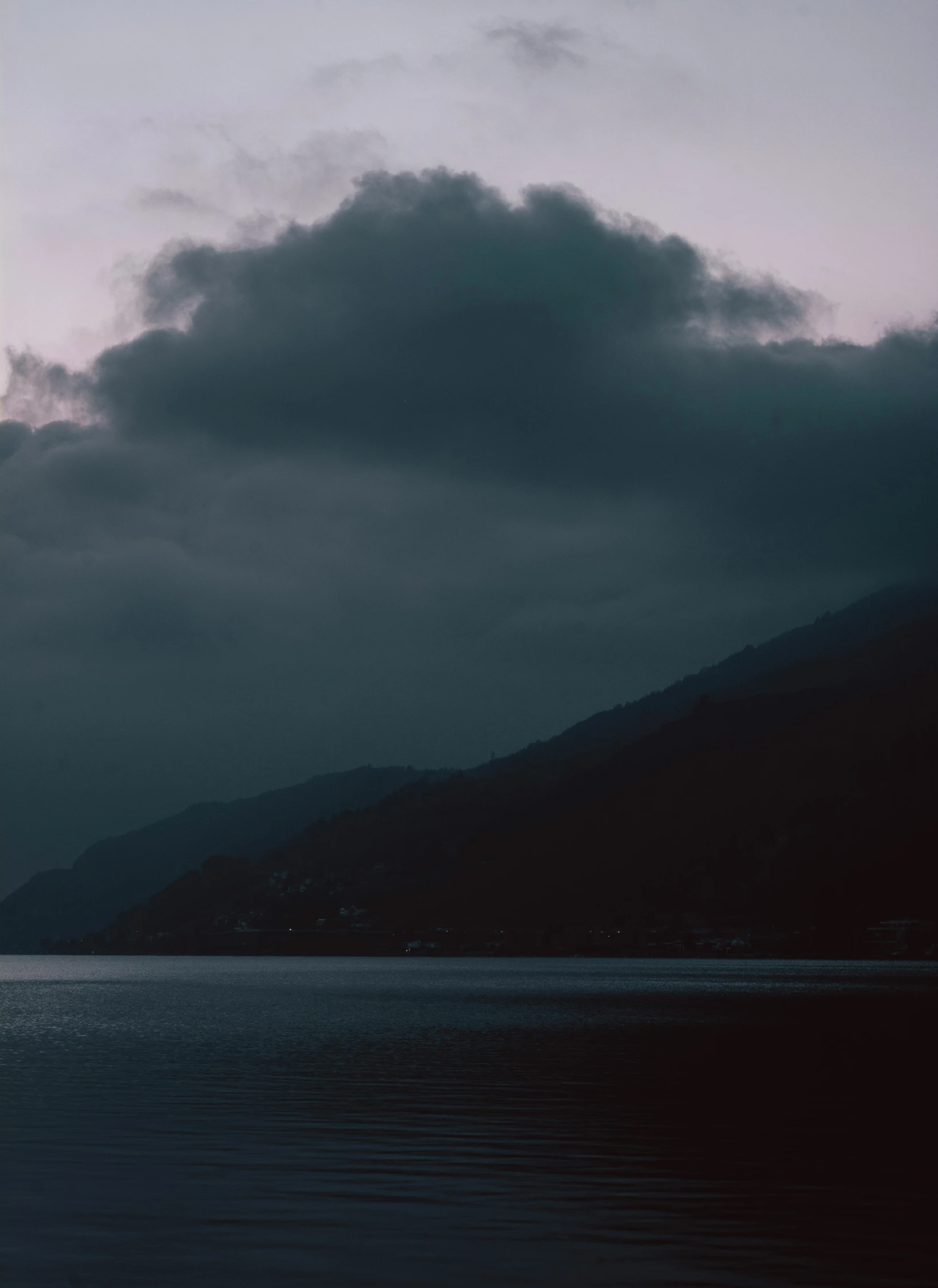 a sail boat on the water with dark clouds in the sky