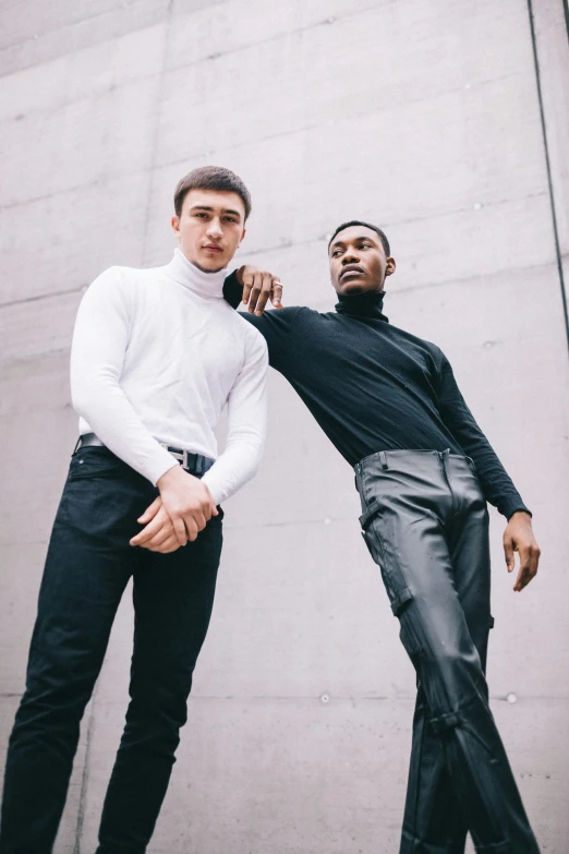 two men are posing outside while one of them looks down