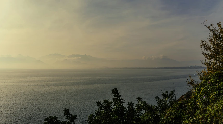 fog hovers over the ocean as distant hills stand on the horizon