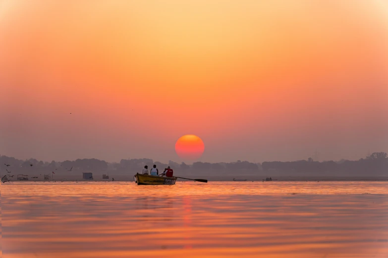 people in small boat at sunset on open body of water