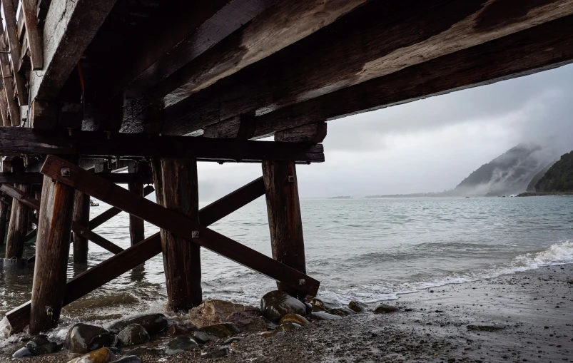 a body of water with waves on it under a wooden beam