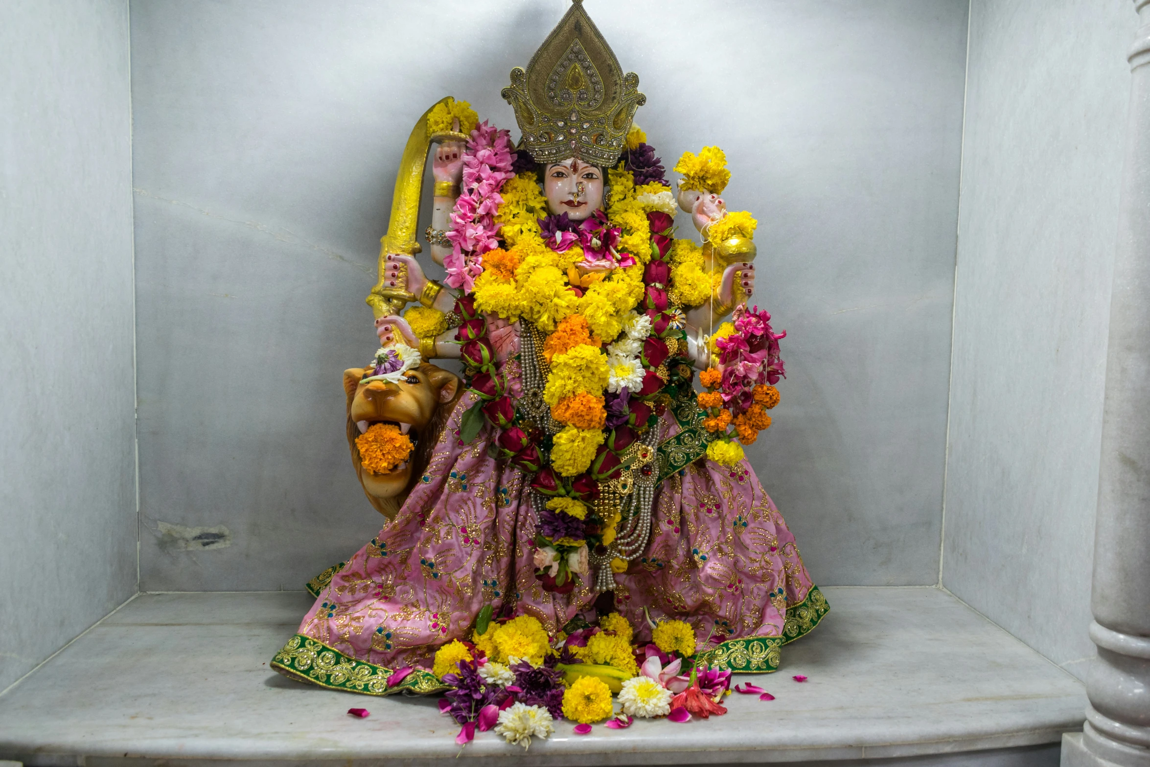 a hindu statue with flowers surrounding it