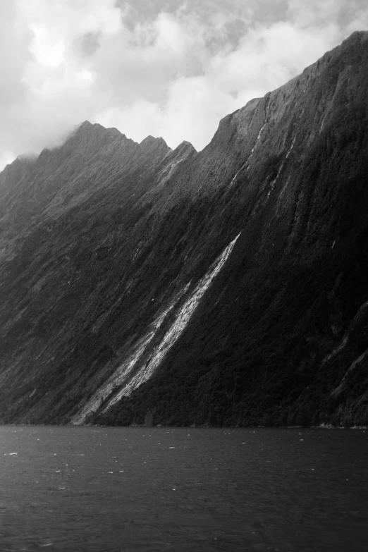 there are mountains behind the water and one boat is sailing