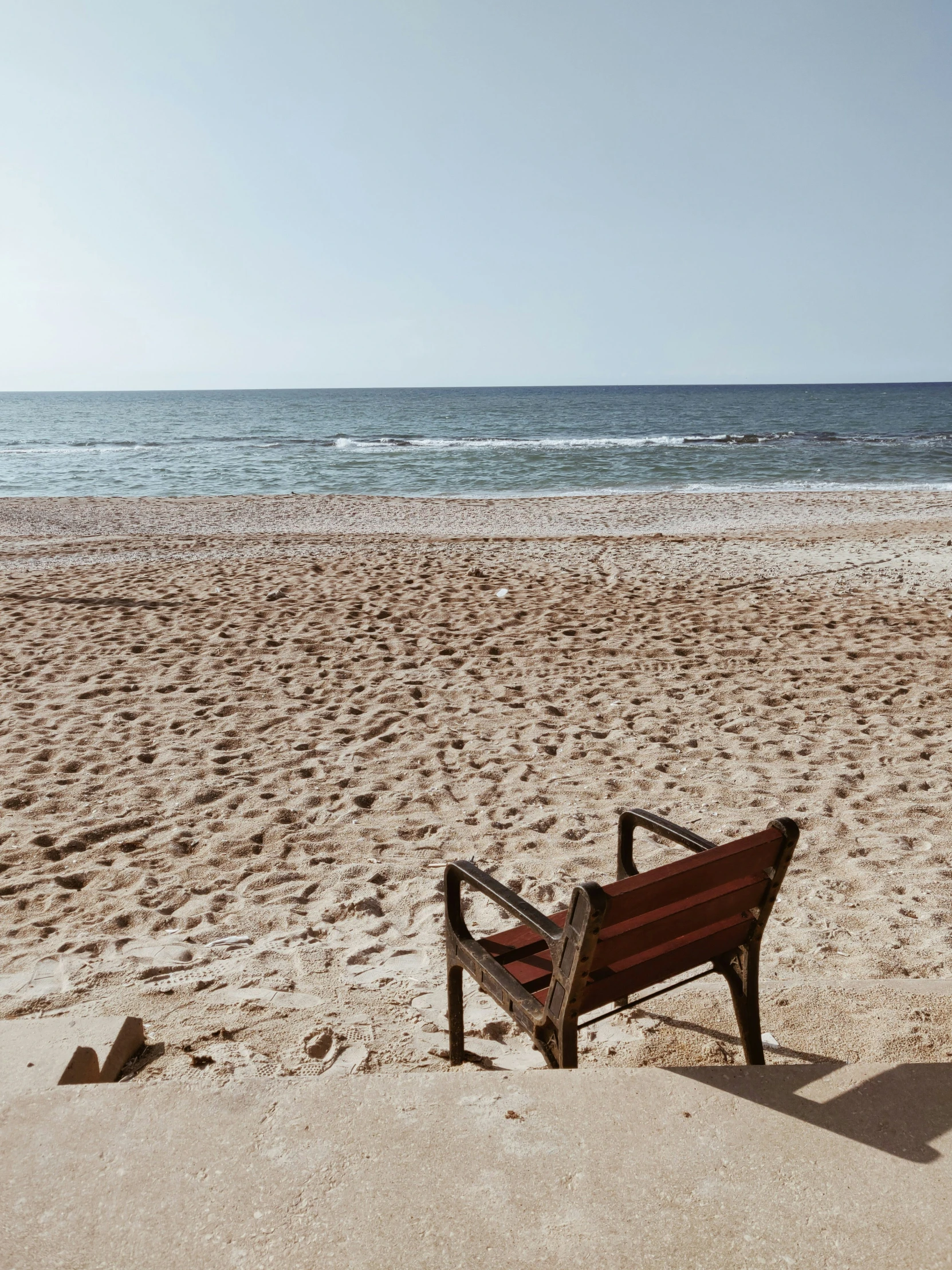 the empty bench is left near the beach