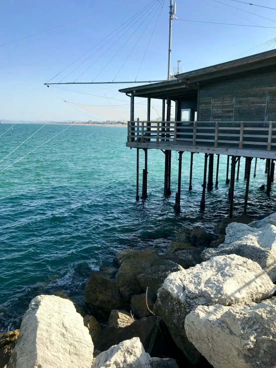 a long dock at the water with rocks in front of it