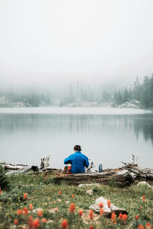 a person sitting next to a body of water with lots of trees