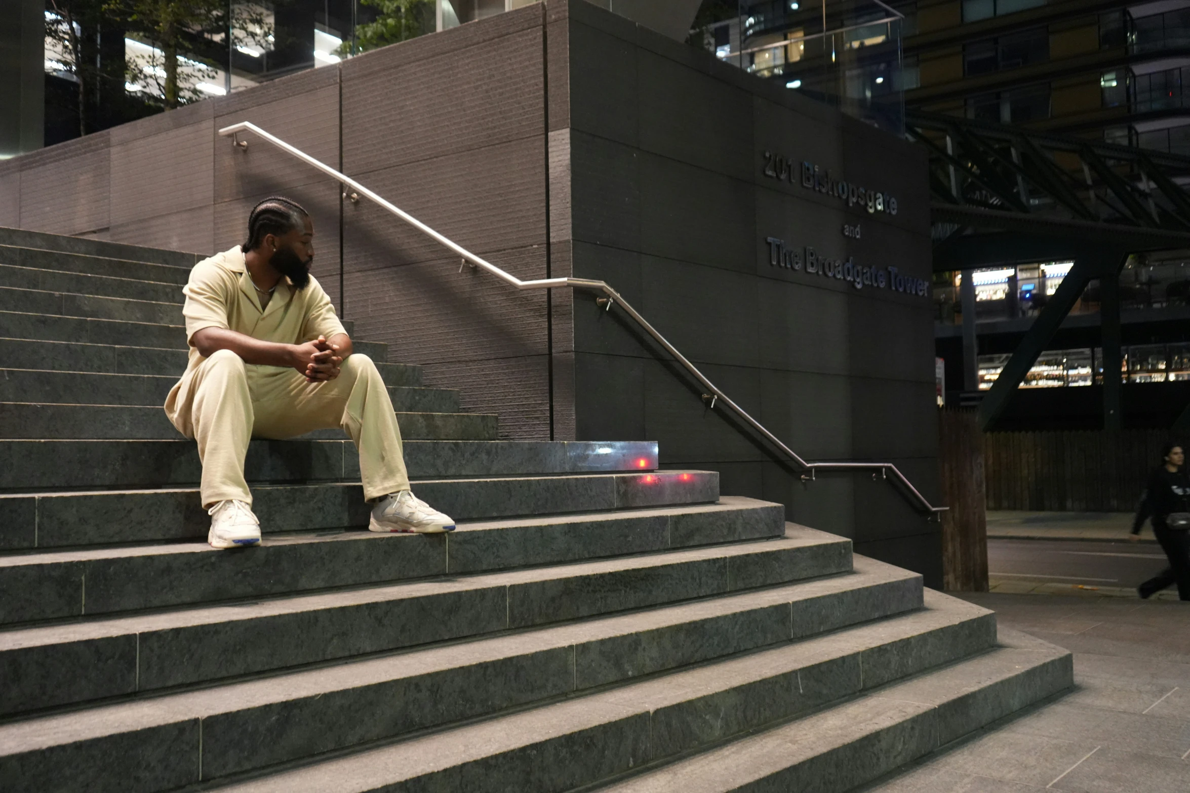 a man in white sits on stairs near stairs