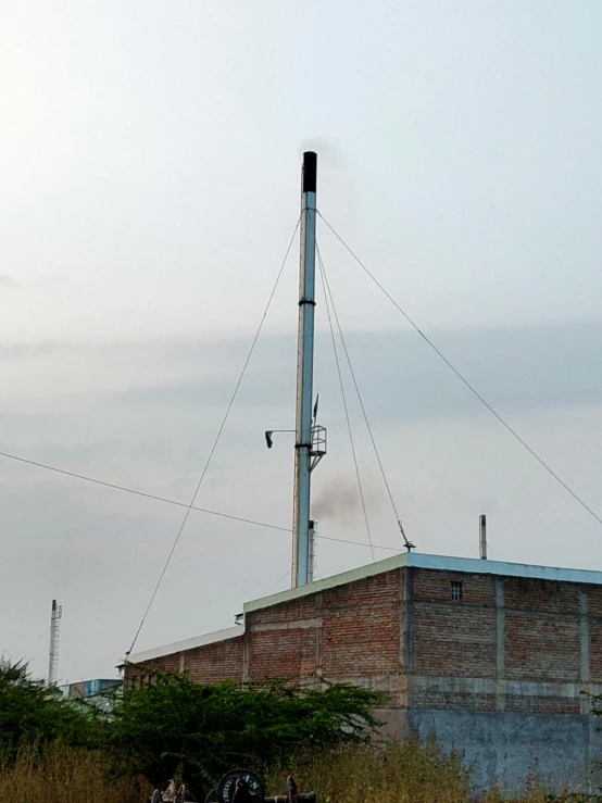 the smoke stack is in the distance behind two small horses