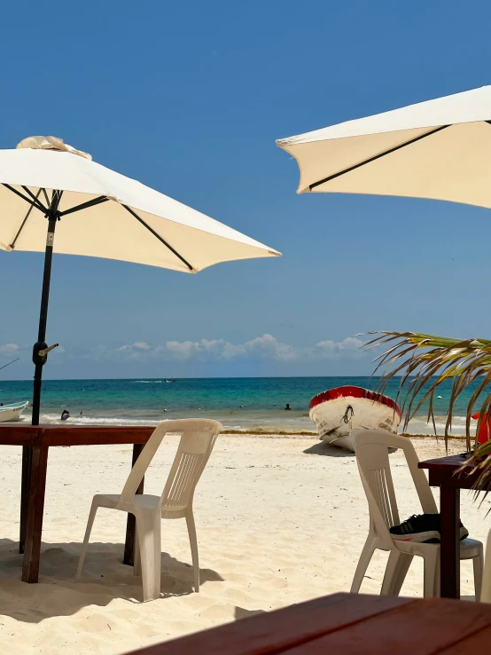 some white chairs under two big umbrellas