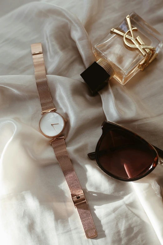 sunglasses and watch lay on white fabric near white tablecloth