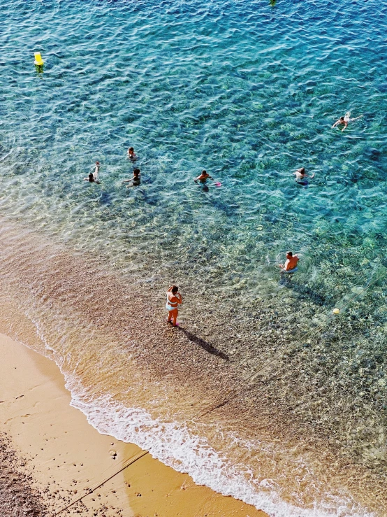 people floating in the water on top of a sandy beach