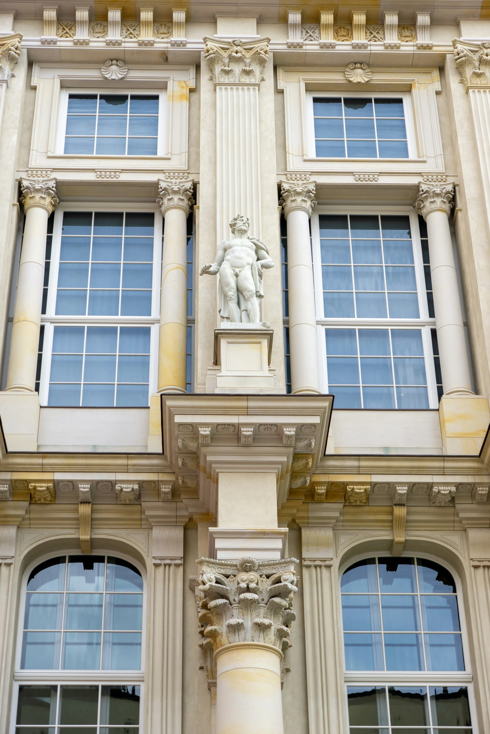 a tall white and beige building with two statues on the sides