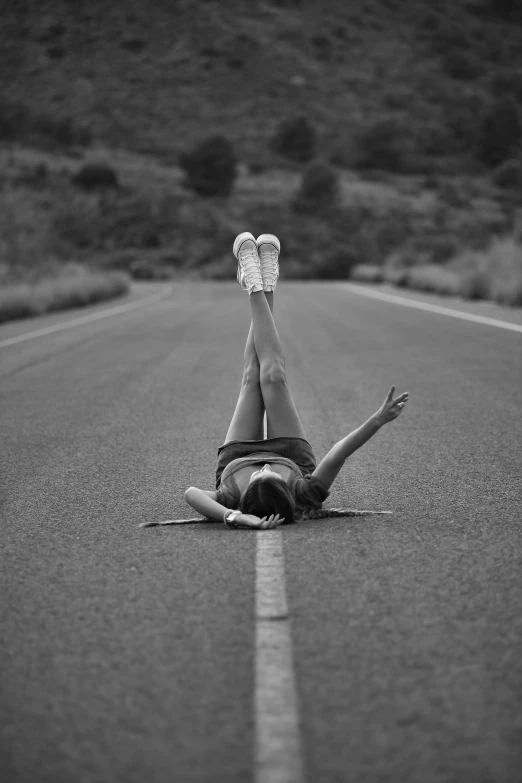 a girl laying on the road with her arms and legs extended