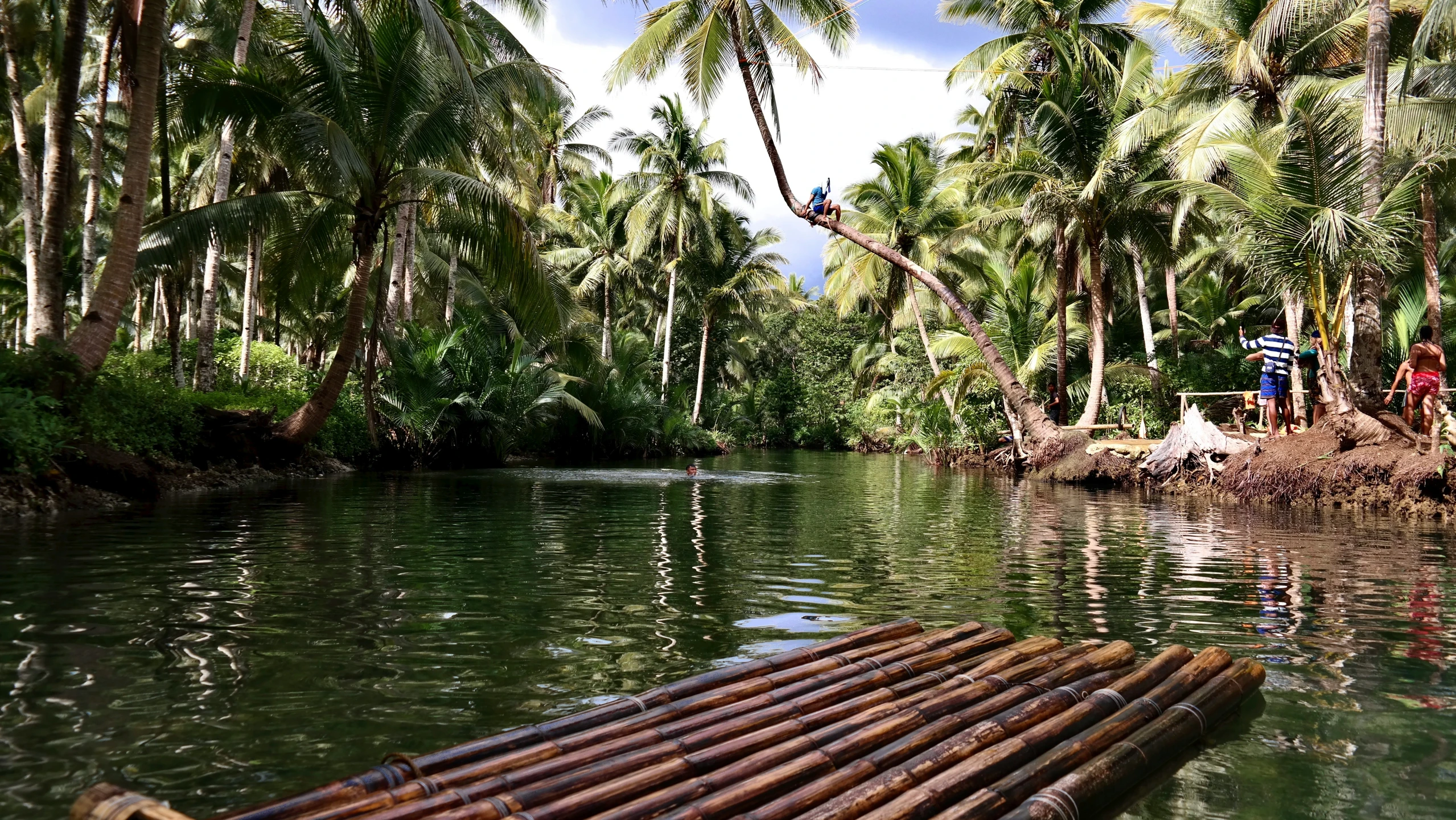 a man on the side of a river with bamboo raft