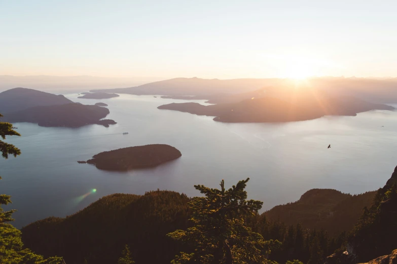 the sun sets over the sea with islands in the water