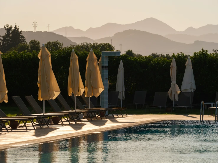 many sun chairs are beside the pool and a mountain range