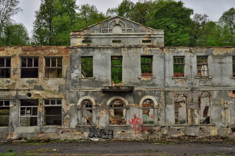 the abandoned building has windows and broken down doors