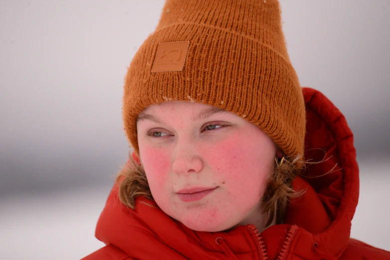 a young woman wearing an orange coat and a beanie