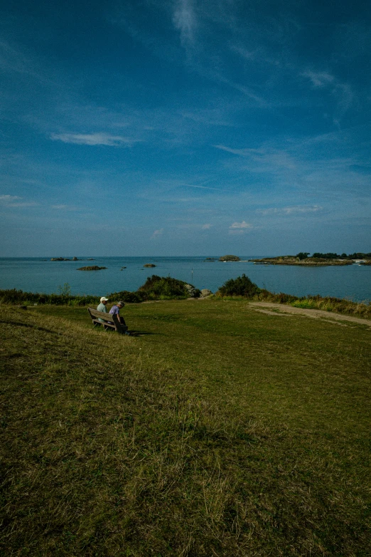 two people sit by the lake on a sunny day