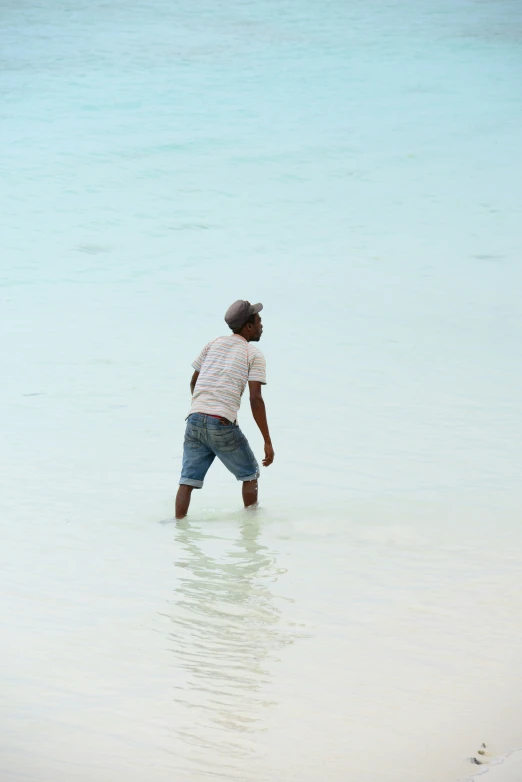a boy stands in shallow water looking for soing