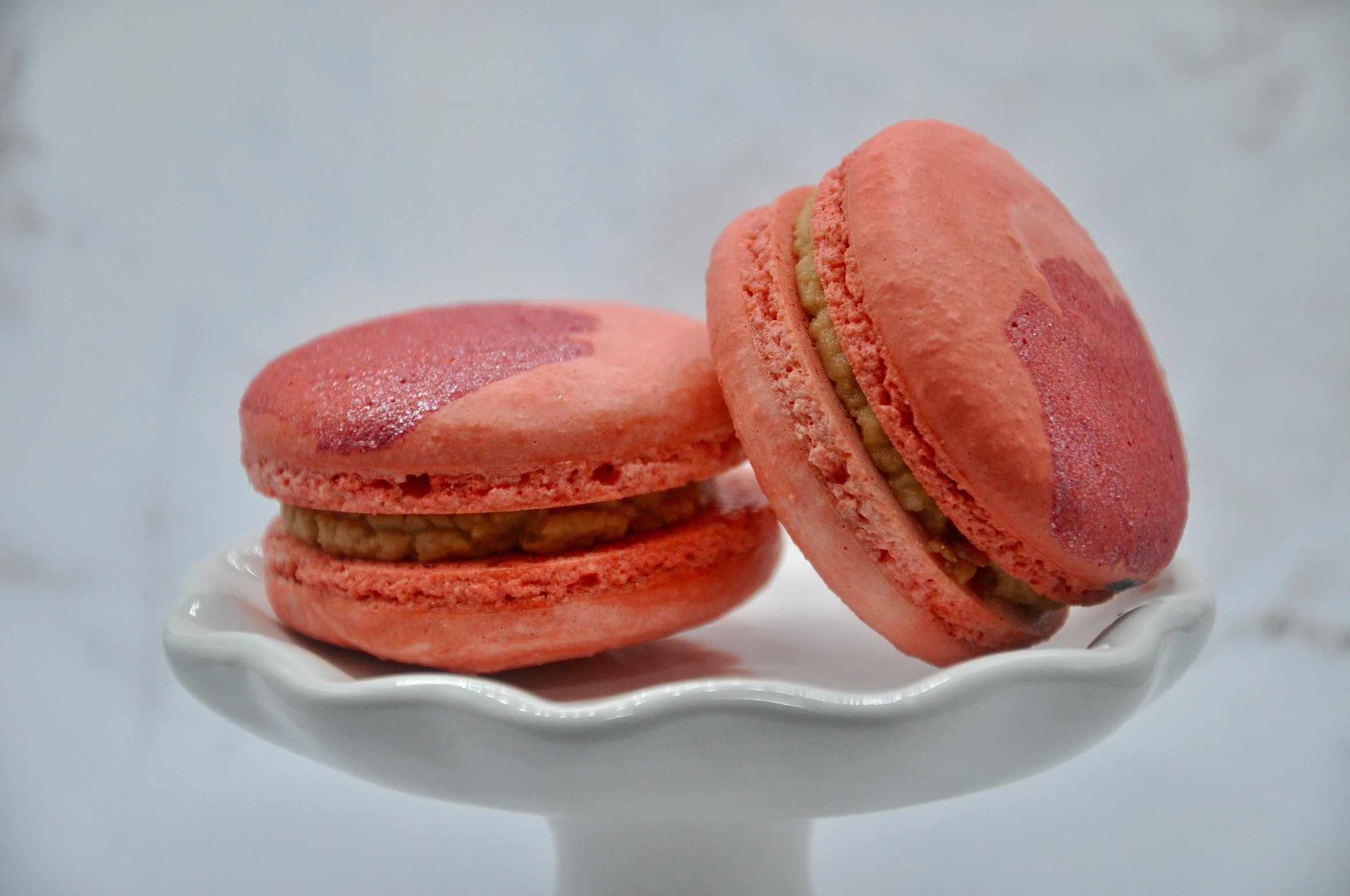 two pink colored cookies sitting on a white bowl