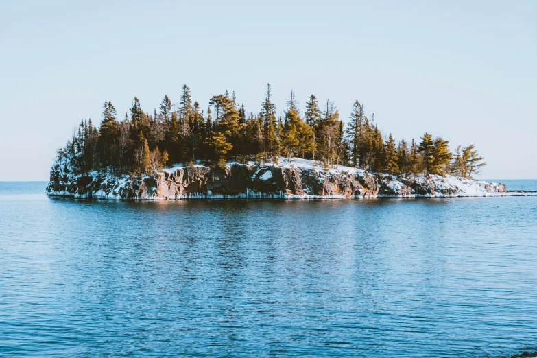 an island with snow covered trees stands in the ocean