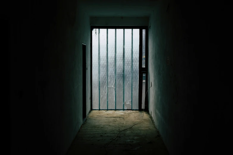 a dark hallway with a thin door and bars