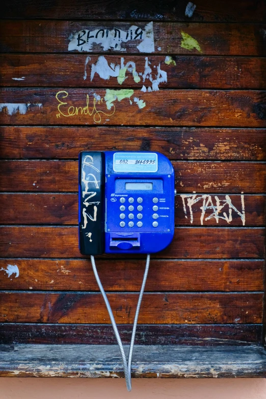 a phone on a telephone booth with graffiti