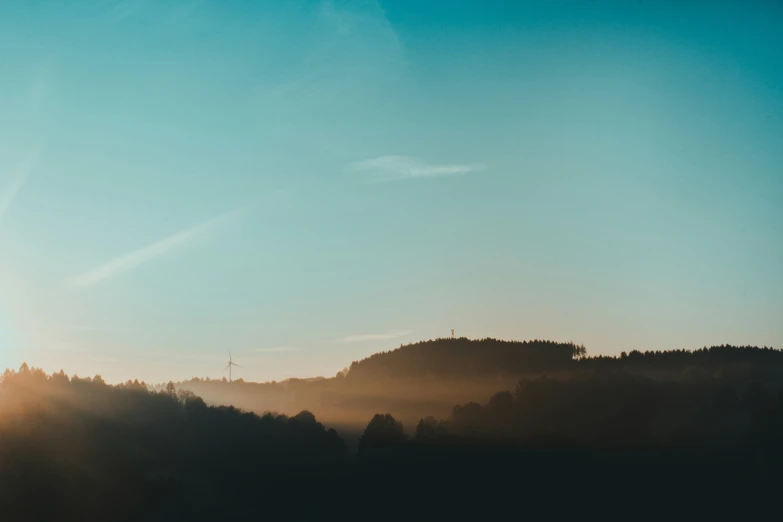 a view of the sun set behind a wooded area