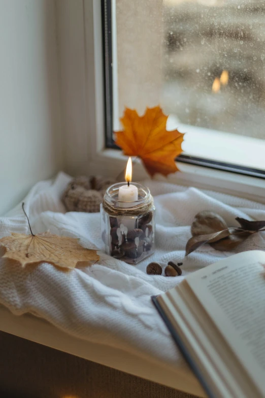 a candle is sitting near an open book on a window sill