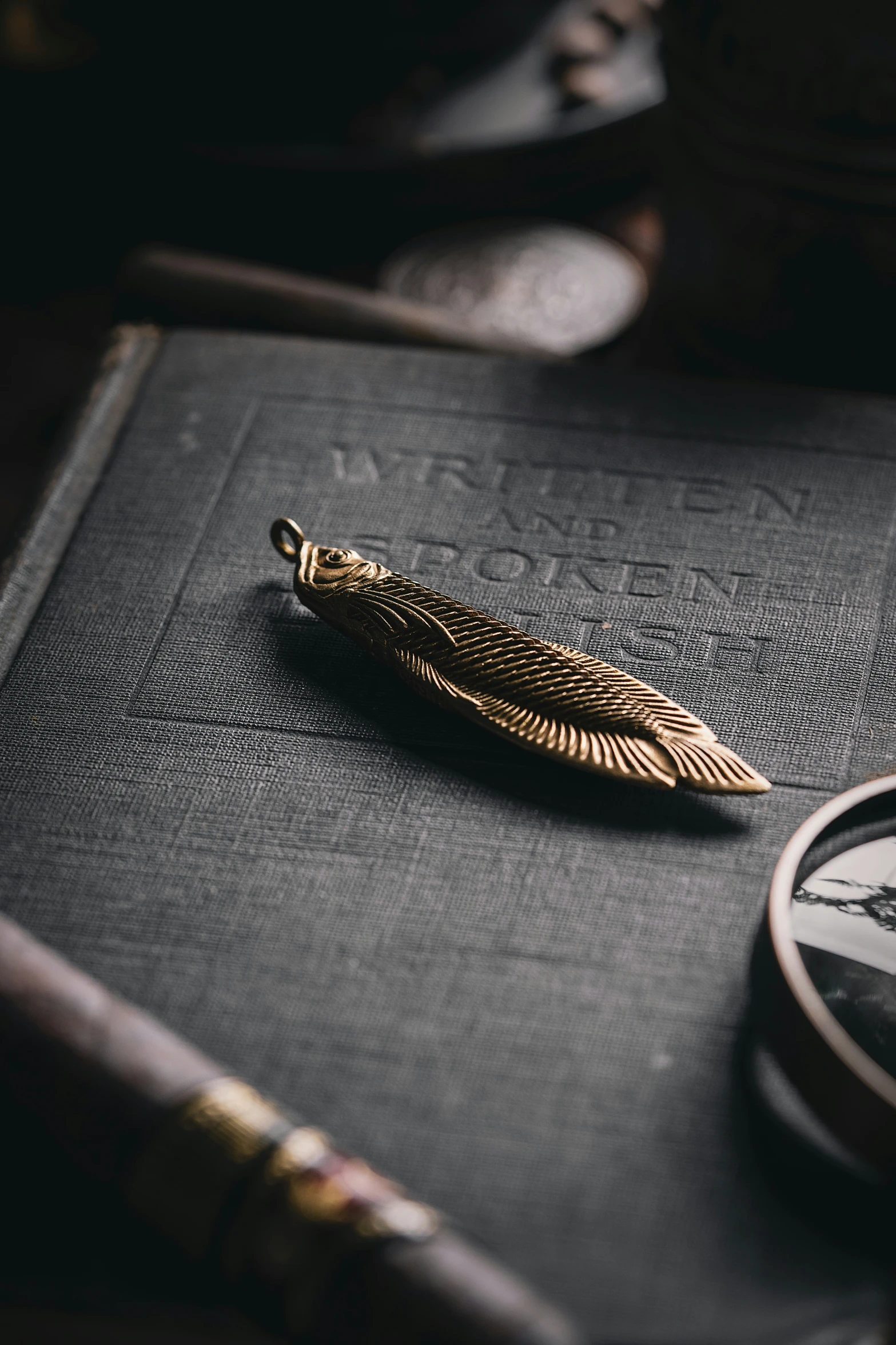 a golden feather brooche is sitting on a book