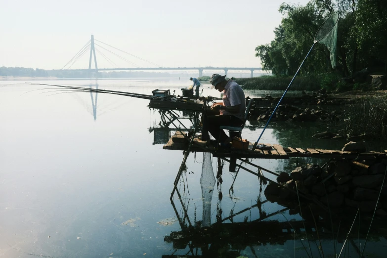 a man that is sitting on a fishing pole