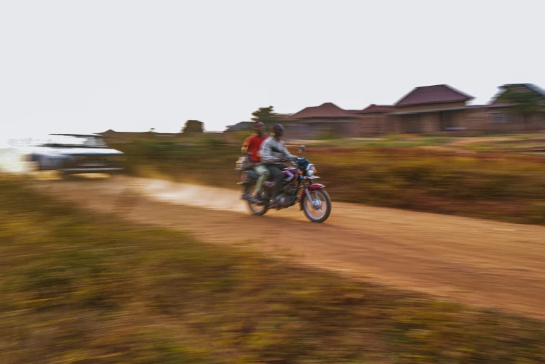 a person on a motorbike rides down a dirt road