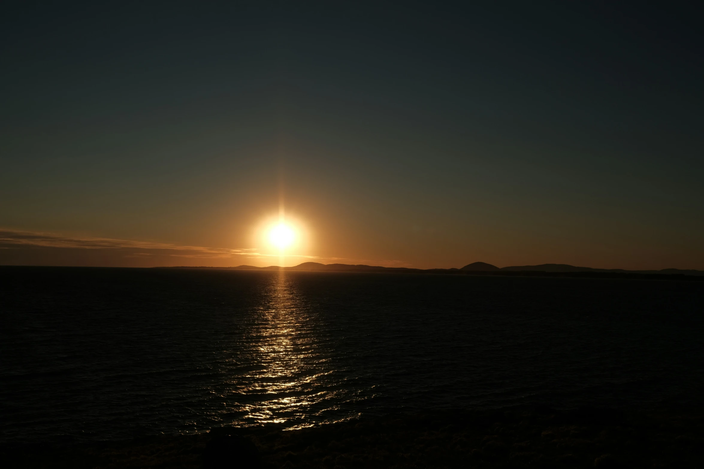 the sun is setting over water and a small island in the distance