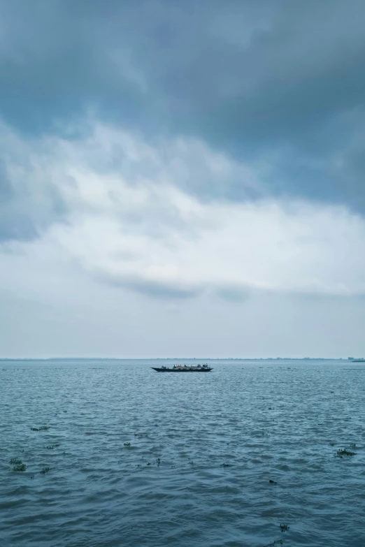 a small boat floating on the ocean on a cloudy day