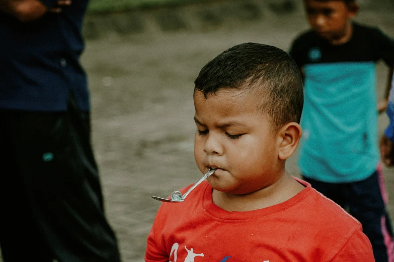 a little boy wearing a shirt while holding soing in his mouth