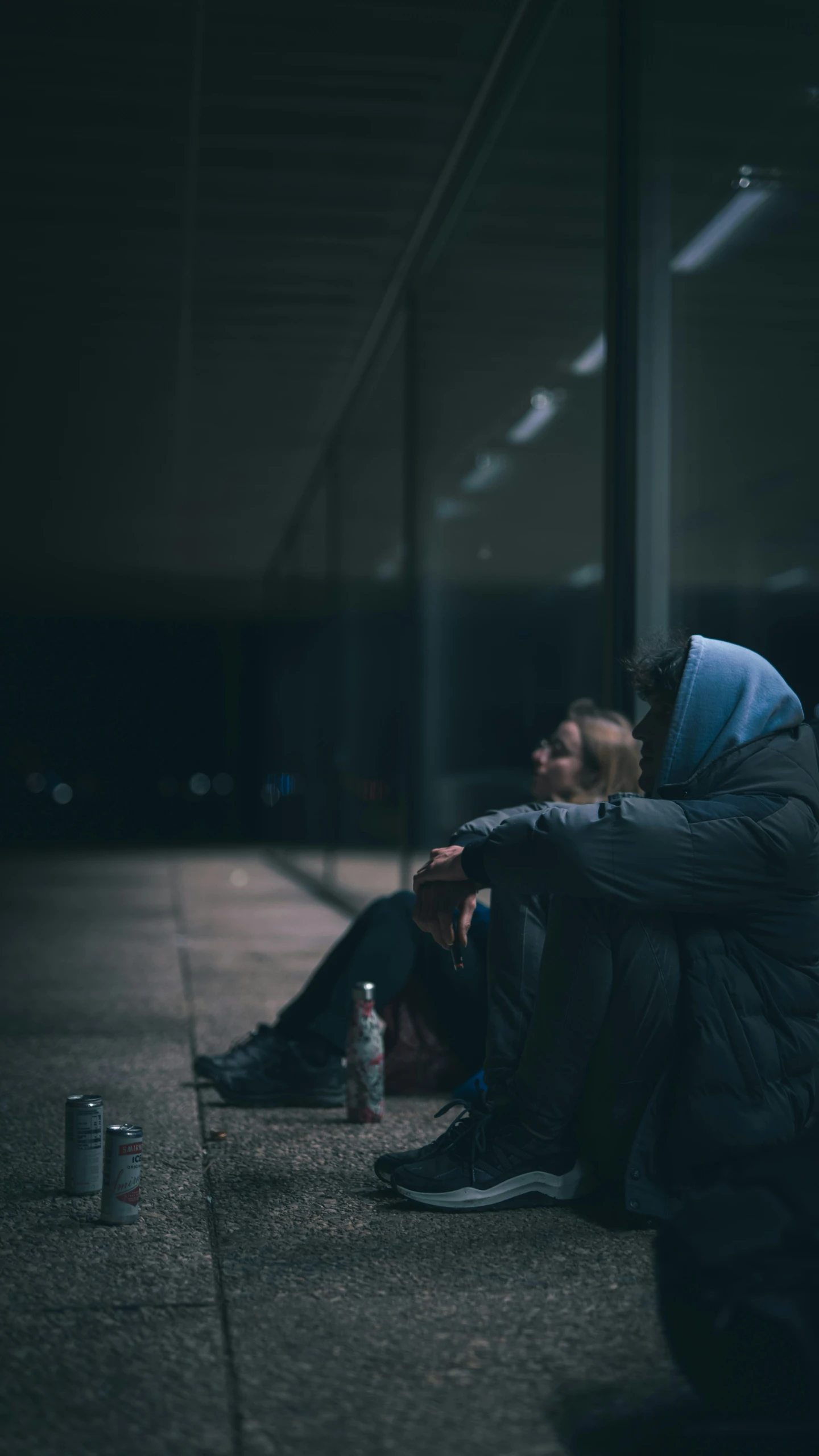 two people sitting on a wall with cans of drinks