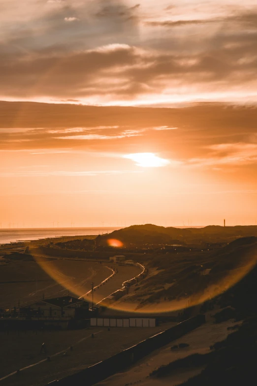 the sun sets over the ocean and the road