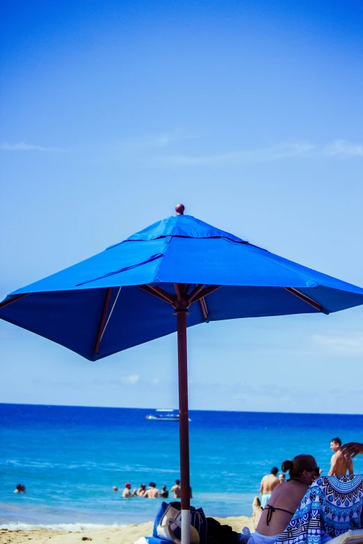 a woman and child are sitting under an umbrella on a beach