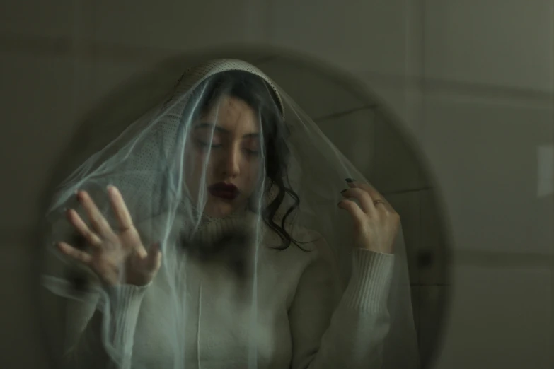 a woman dressed in white hiding behind a veil