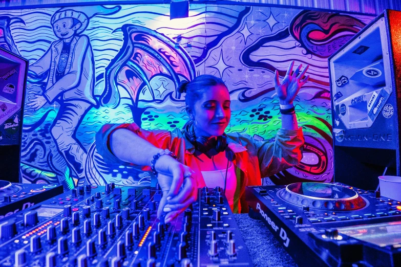 a dj mixing at his mixing booth with an assortment of music devices