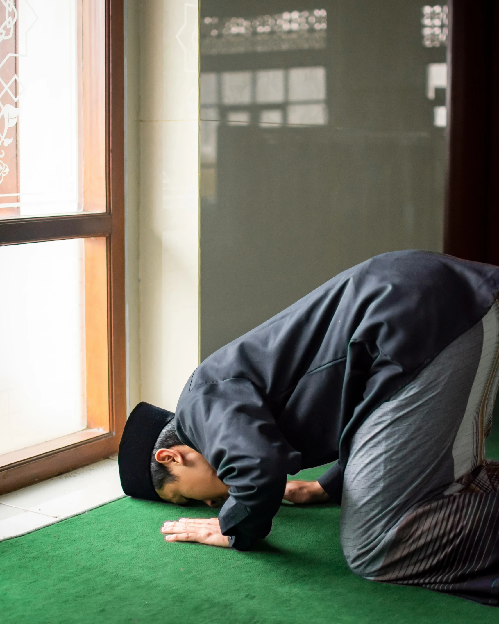 a man dressed in black standing on his knees and looking at his head on the ground