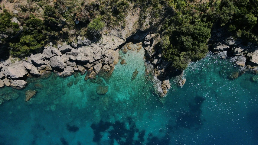 an aerial view of rocks and water along with trees