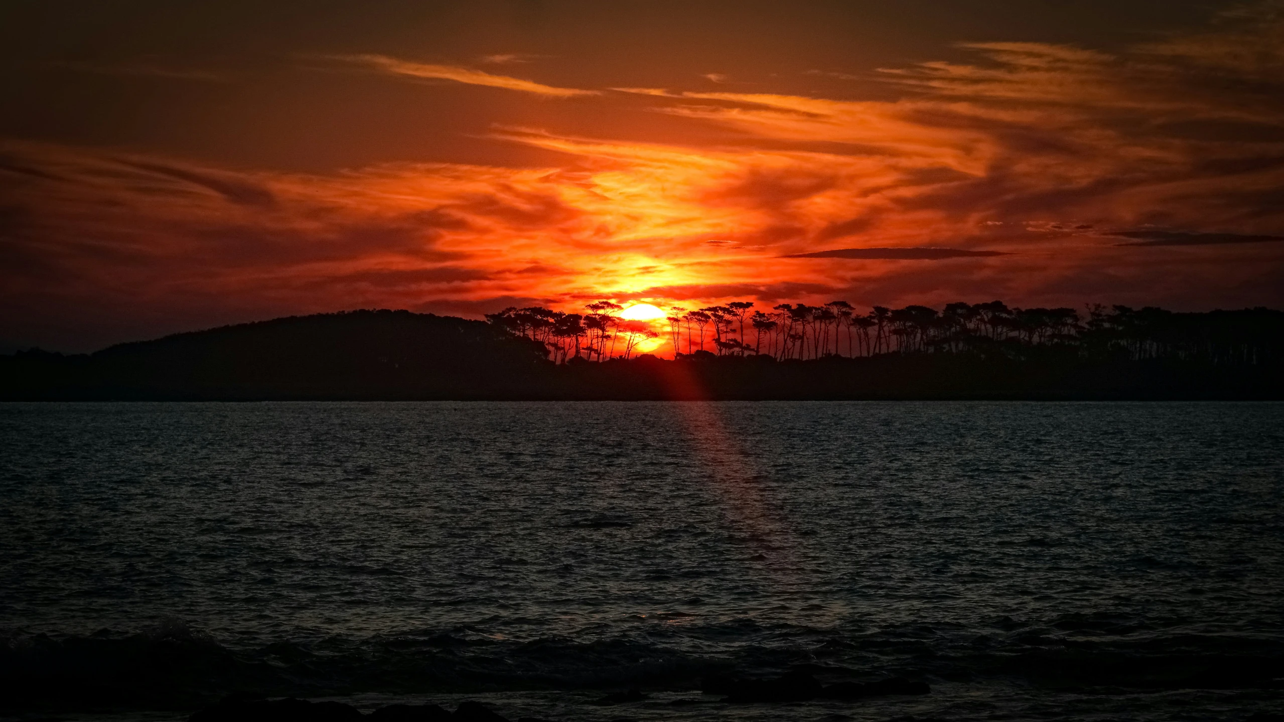 the sun is setting in the middle of the water